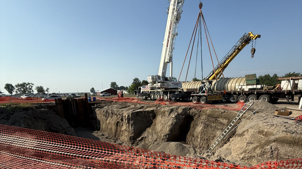 Tank being set in large hole in the ground.